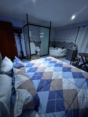 Camera d'albergo con un letto, una scrivania, una sedia, una vasca da bagno e una porta vetrata che conduce al bagno.