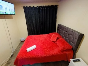 A room with a bed, a television, and a curtain. - La Cachaca (BOGOTÁ)