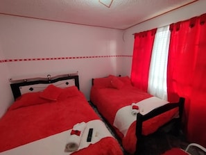 A room with two beds, each with red bedding and a wooden headboard. - La Cachaca (BOGOTÁ)
