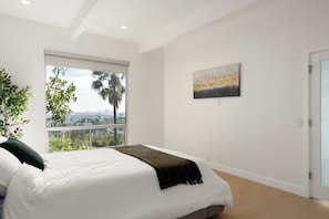 A bedroom with a bed, a window with a view, and a painting on the wall. - Iconic Hollywood Panoramic Perch (Los Angeles)