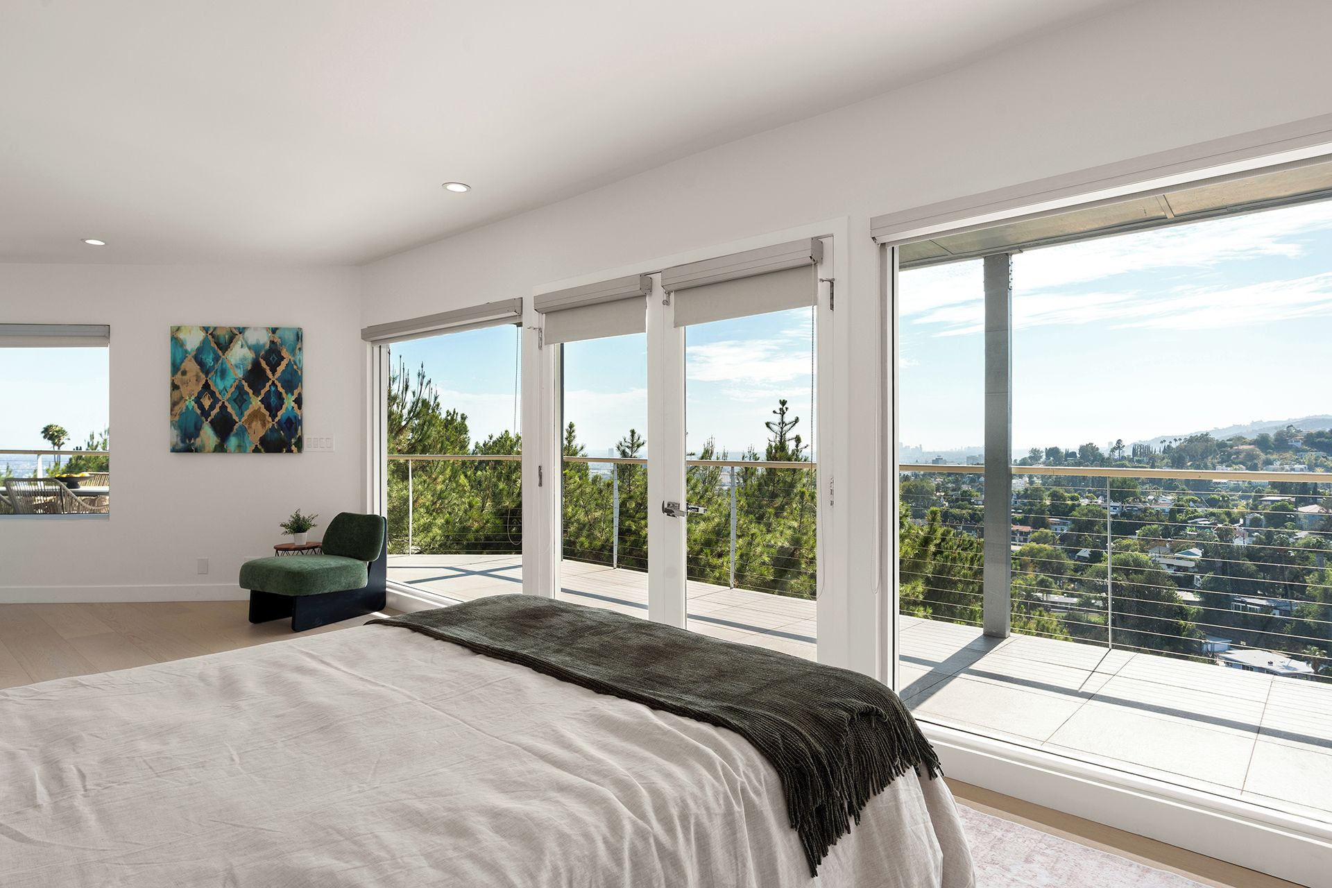 Une chambre avec un grand lit, une vue sur la ville et un balcon avec une balustrade.