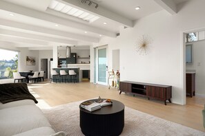 A modern living room with a sofa, a coffee table, and a dining area with chairs and a table. - Iconic Hollywood Panoramic Perch (Los Angeles)
