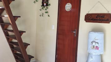 A wooden staircase, a door with a sign, a small shelf, and a water dispenser.