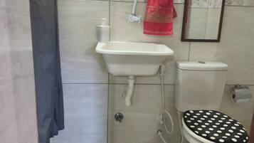 A bathroom with a toilet, sink, and mirror. There are two black and white polka dot mats on the floor.