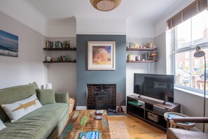 Ein Wohnzimmer mit Kamin, Fernseher und Bücherregalen.