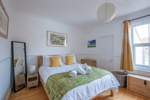 Ein Hotelzimmer mit einem Bett, einem Nachttisch, einer Lampe, einem Gemälde, einer Tür und einem Fenster mit Vorhängen.