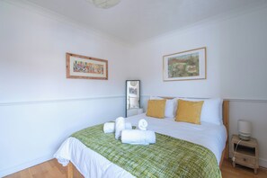 Una habitación de hotel con una cama, una mesita de noche, una lámpara y dos cuadros en la pared.