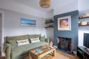 Una sala de estar con un sofá verde, chimenea y estantería.