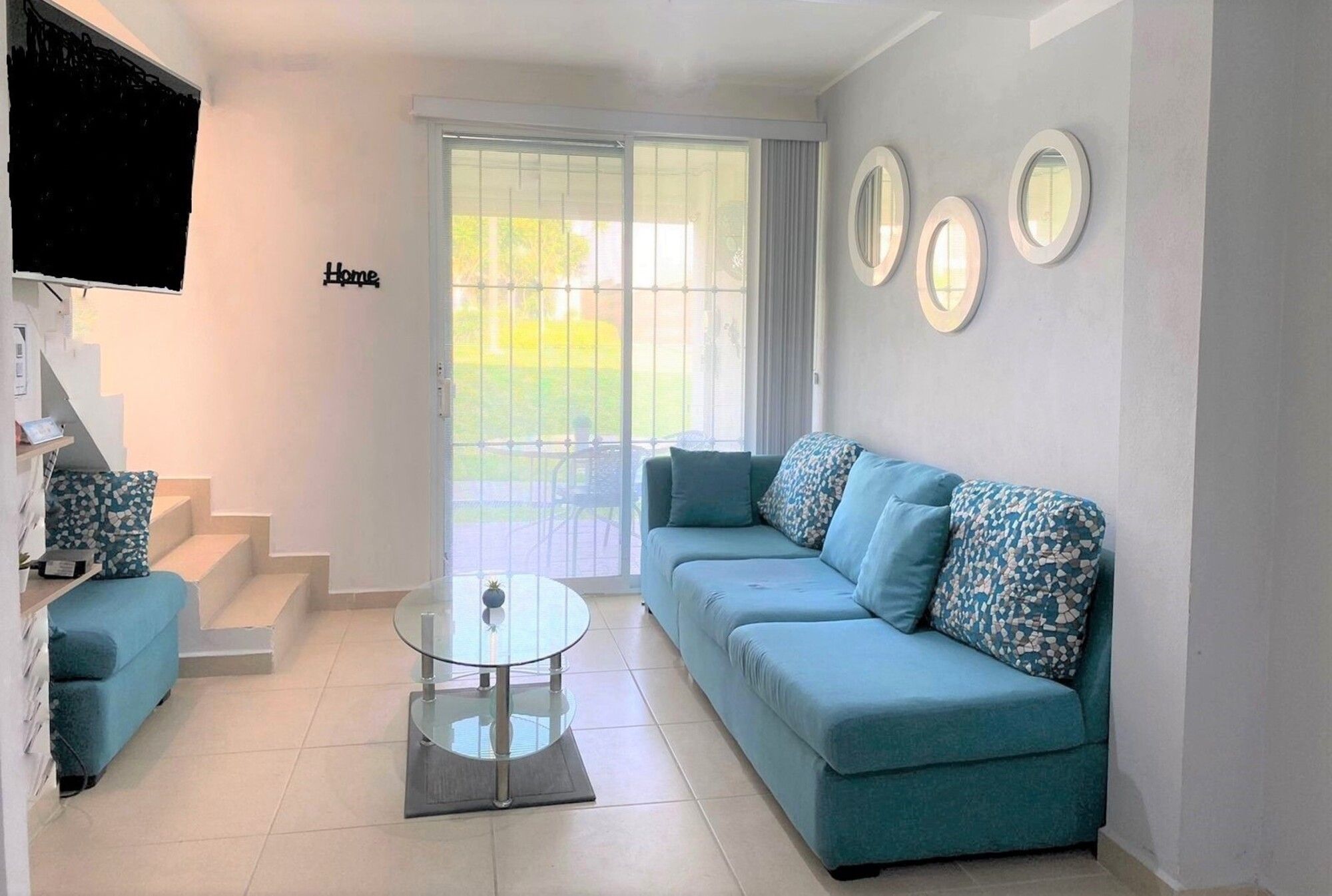 A living room with a sofa, a coffee table, and a TV mounted on the wall.