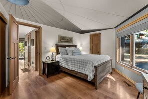 A bedroom with a bed, bedside tables, a window, and a door leading to another room. - Riverfront Ski Cabin W/ Hot Tub & Dock! (Bend)