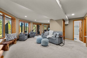 A spacious living area with a grey sofa, ottomans, and a wooden bench. - Riverfront Ski Cabin W/ Hot Tub & Dock! (Bend)