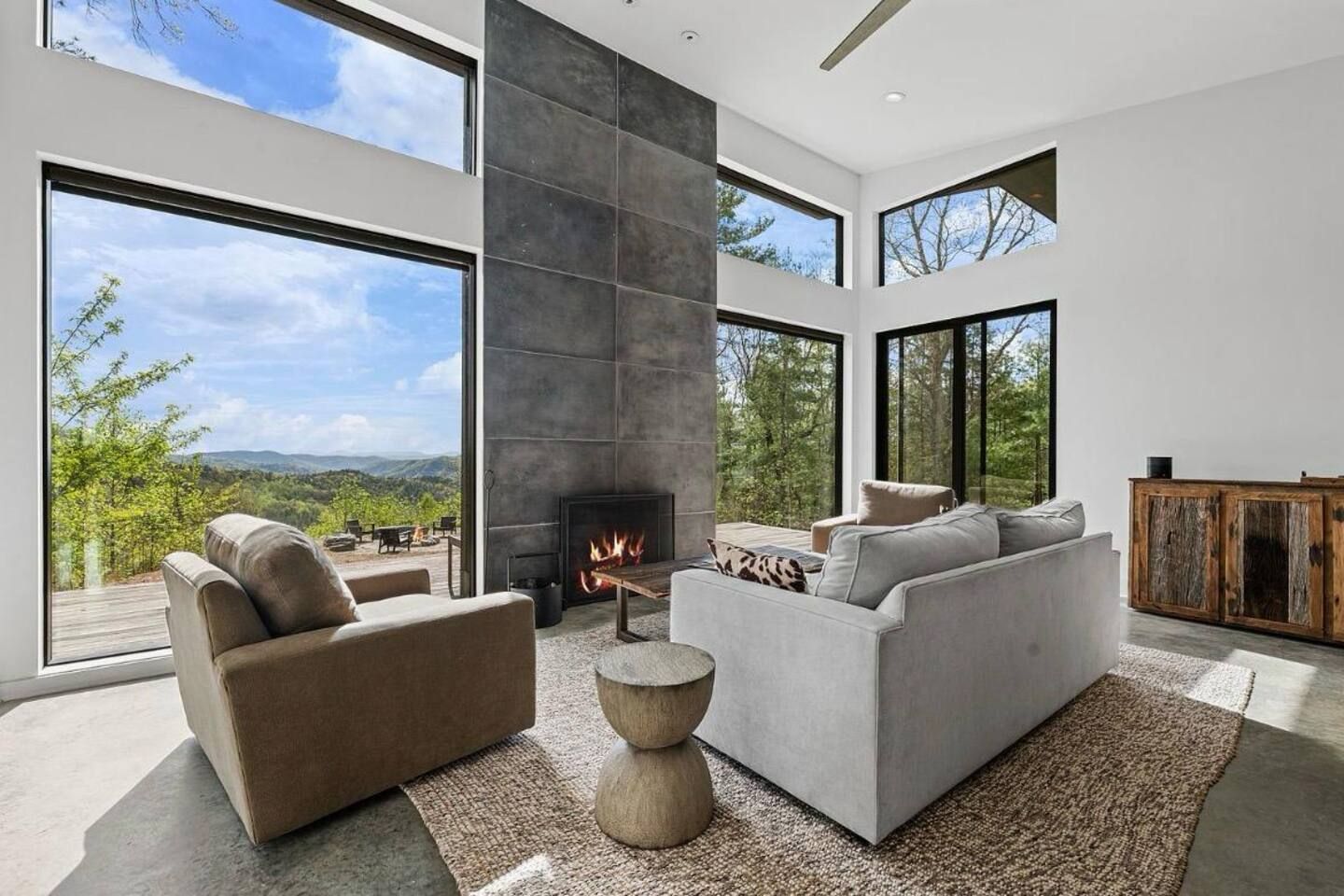 Una sala de estar moderna con chimenea, ventanas amplias y vistas al exterior.