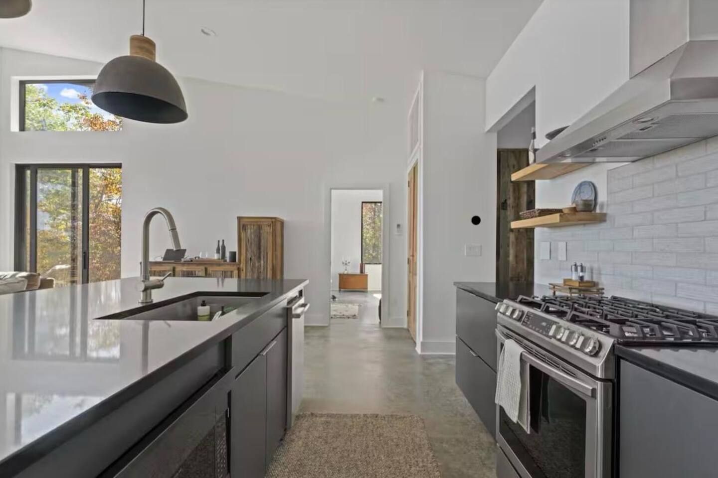A modern kitchen with a central island, stainless steel appliances, and a view to the outdoors.