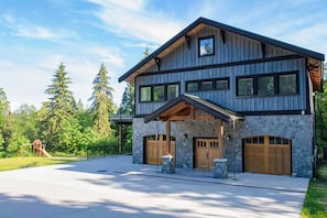 Ein zweigeschossiges Haus mit einer Stein-Fassade, großen Fenstern und einer Garage.