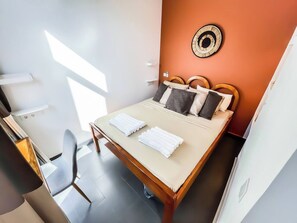 Ein Hotelzimmer mit einem Bett, einem Sessel, einer Wanduhr und einem Fenster.
