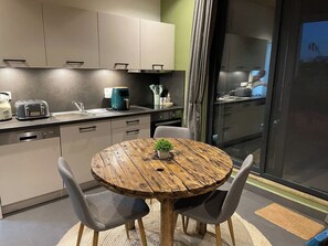 Une cuisine moderne avec une table ronde en bois, des chaises grises et une petite plante en pot.