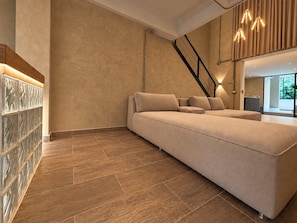 Ein modernes Wohnzimmer mit einer großen Couch, einer Treppe und einer Glaswand.