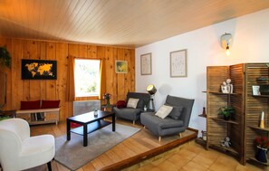 Ein gemütliches Wohnzimmer mit Holzwänden, einer Couch, einem Couchtisch und einem Bücherregal.
