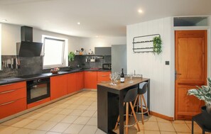 Une cuisine moderne dotée d’un îlot central, d’un coin repas et d’une porte en bois.