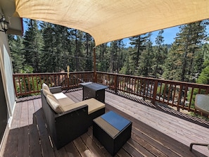 Eine Holzterrasse mit Gartenmöbeln, einer Pergola und Blick auf einen Wald.