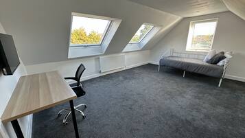 A room with a bed, a desk, and two skylights.