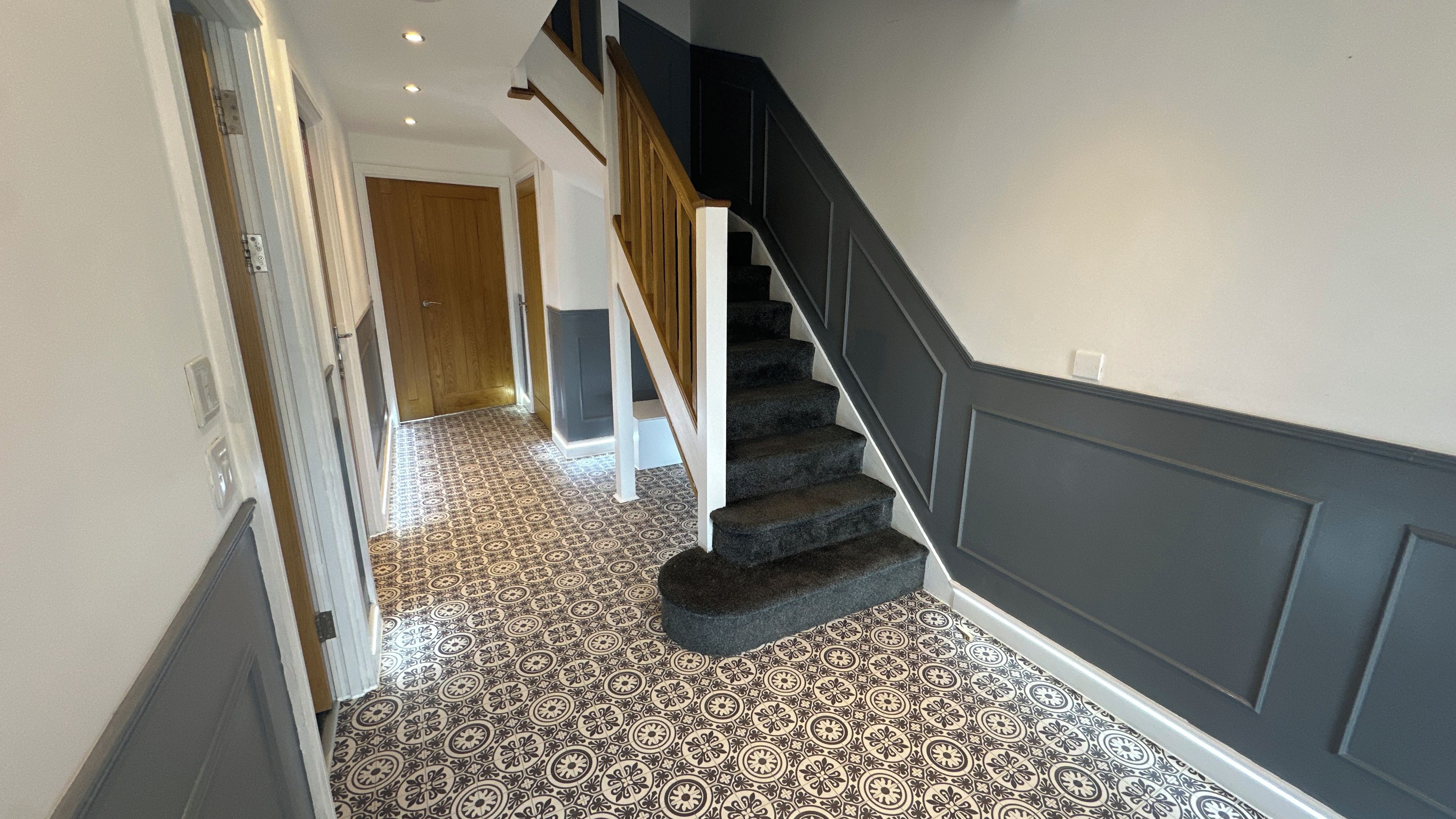 A staircase with a patterned floor leading to a landing.