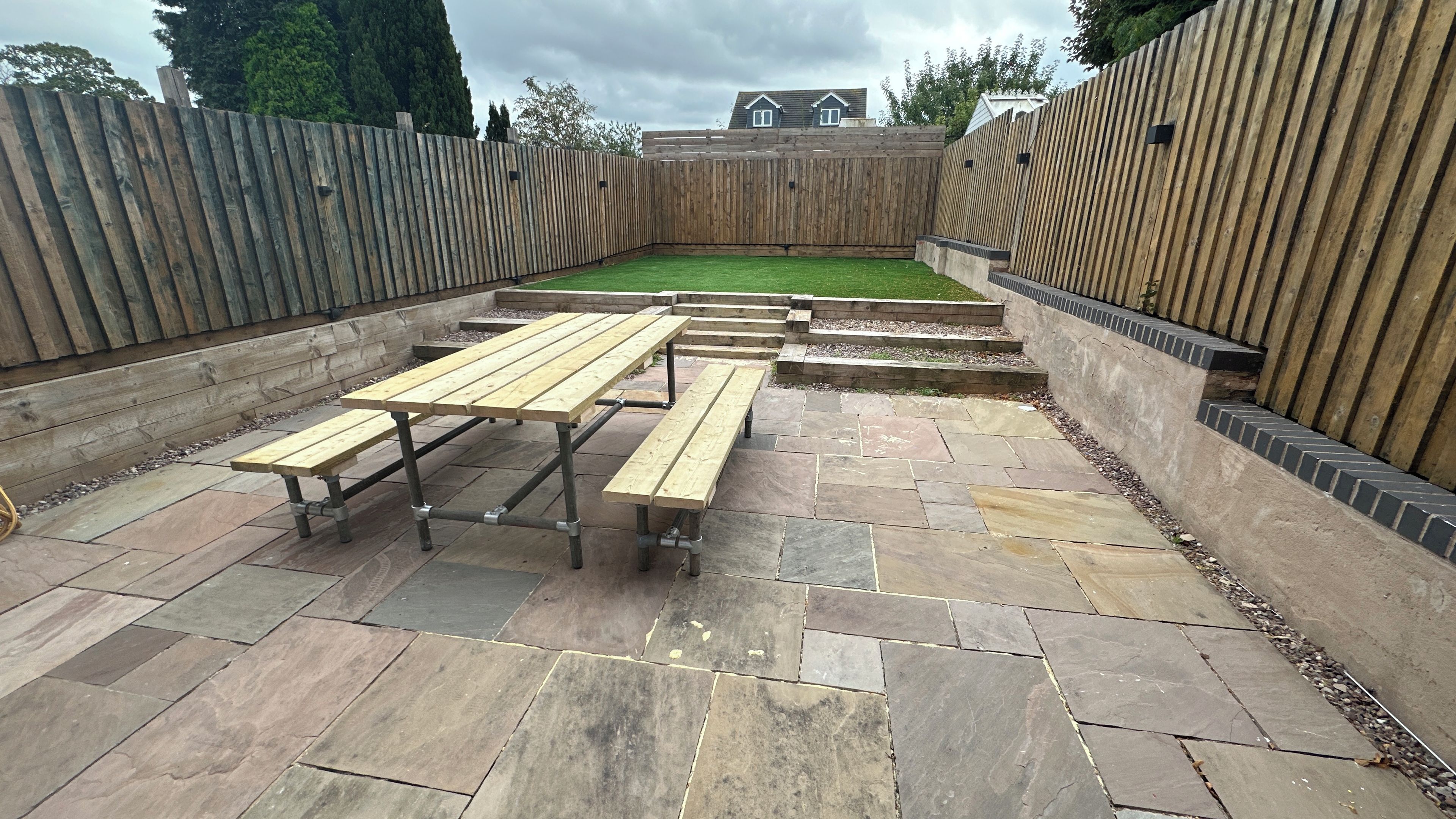 A patio area with stone flooring and wooden benches.