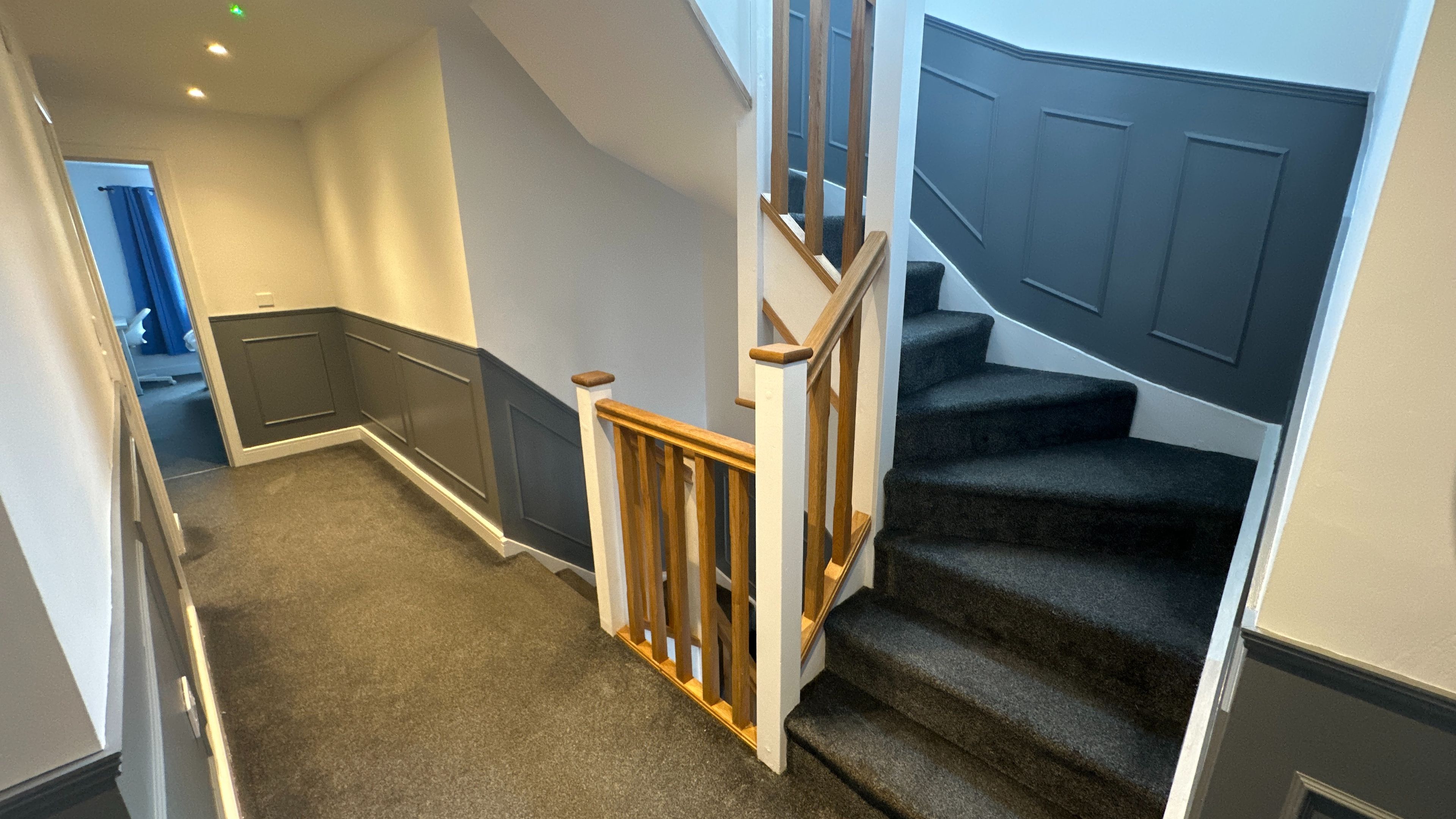 Una escalera con barandillas de madera y peldaños alfombrados que conducen a una plataforma.