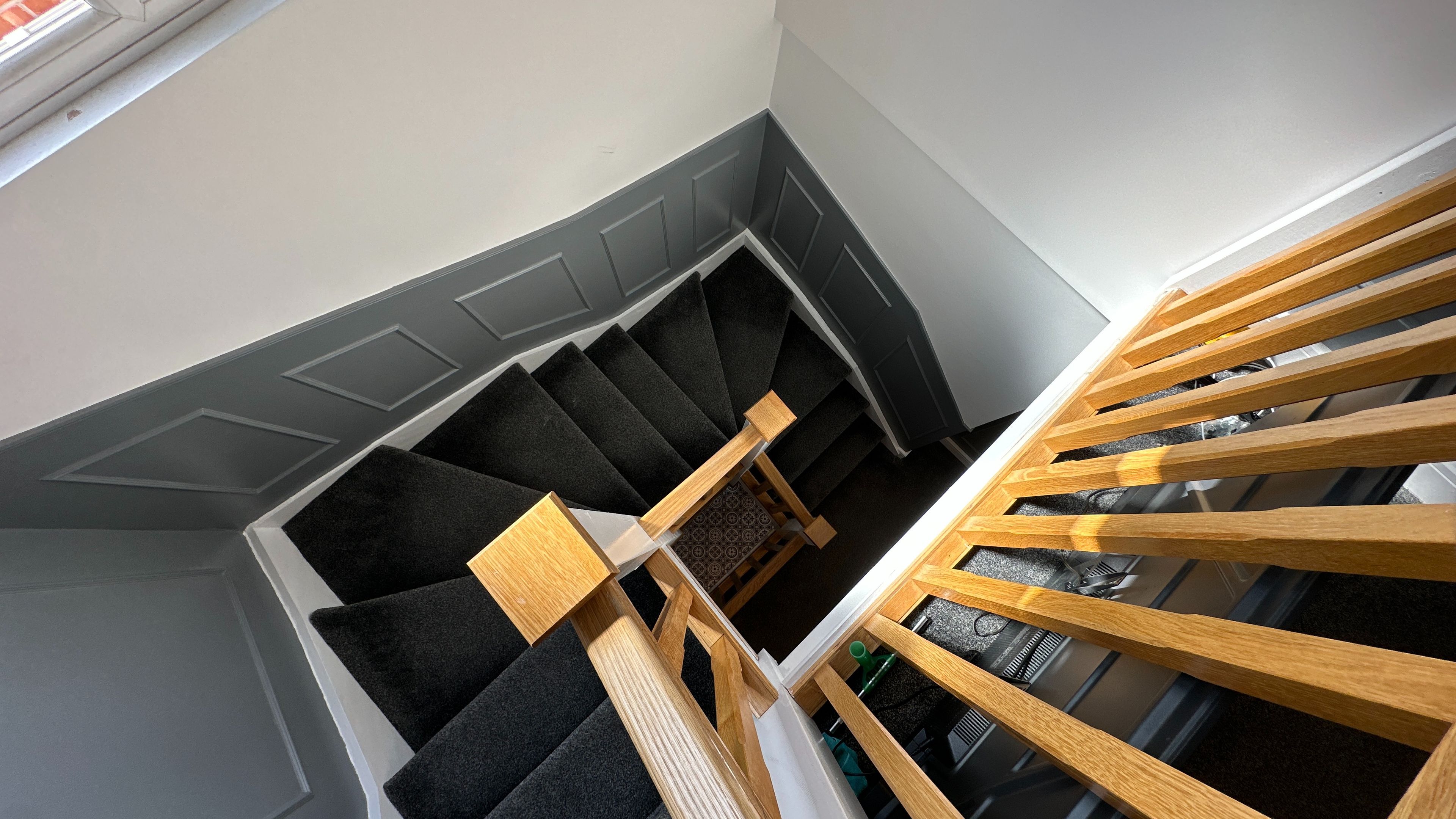 Una escalera de caracol con barandilla de madera y escalones alfombrados.