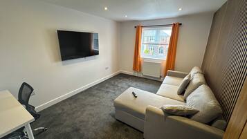 Modern lounge with plush sectional and large wall-mounted TV
