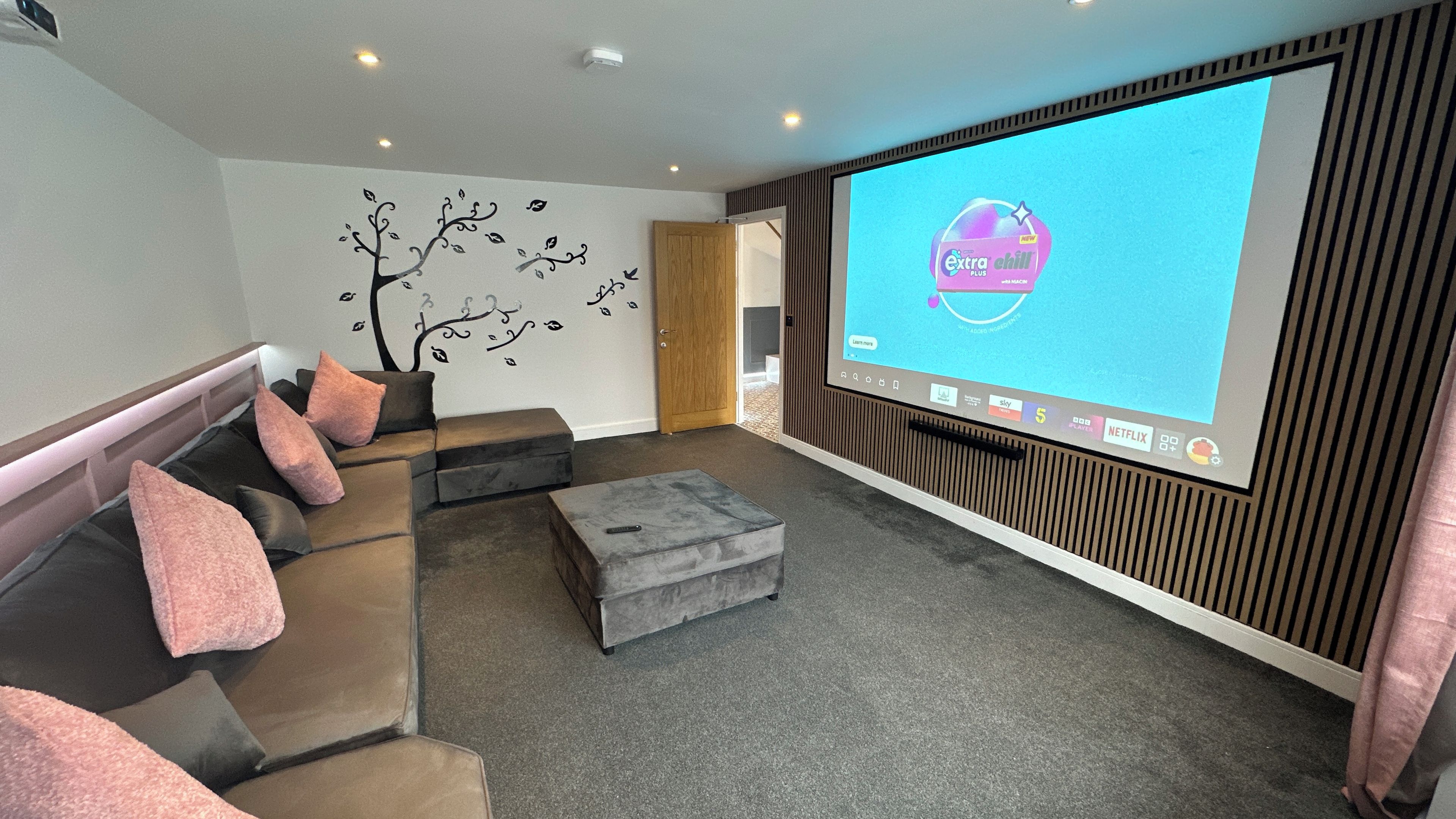 Private home cinema with big screen, plush seating, and cozy ambient lighting