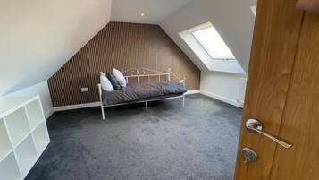 Bright loft bedroom with skylight and stylish wood accent wall