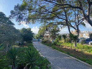 A paved pathway lined with trees and greenery, leading to a building with a bell tower. - Calm 1BR Apartment in Pietà with Balcony (Tal-Pietà)