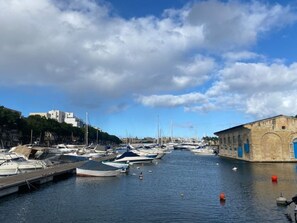 A marina with boats docked, a clear sky, and a building on the right. - Airy 1BR Apartment in Pietà with Balcony (Tal-Pietà)