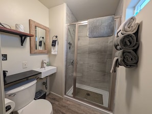 Een badkamer met toilet, wastafel, spiegel, douche en handdoeken.
