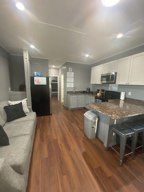 A modern kitchen with a microwave, stove, and granite countertop. There is a trash can and a refrigerator with a water dispenser. - Blue crab house boat, Wi-Fi, Ice machine, sleeps 8,perfect place to fish (Venice)