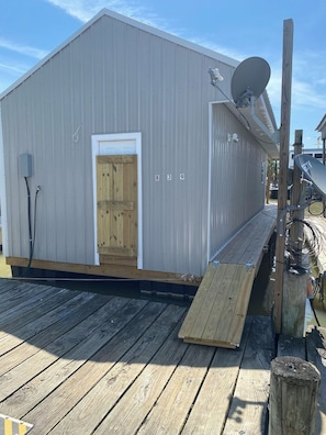A metal building with a door, a ramp, and a satellite dish. - Blue crab house boat, Wi-Fi, Ice machine, sleeps 8,perfect place to fish (Venice)