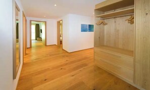A hallway with wooden flooring, a wooden wardrobe, and a door leading to another room. - DESIGNED TO COMBINE CONTEMPORARY COMFORT WITH THE CHARM OF SWISS ALPS-ZERMATT (Zermatt)