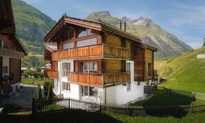A two-story chalet with balconies, set against a mountainous backdrop. - DESIGNED TO COMBINE CONTEMPORARY COMFORT WITH THE CHARM OF SWISS ALPS-ZERMATT (Zermatt)