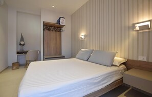 Ein Schlafzimmer mit Bett, Nachttisch, Wandlampe und Schreibtisch mit Stuhl.