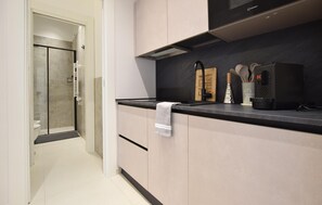 Eine moderne Küche mit schwarzem Arbeitsplatz, Edelstahlgeräten und einem Handtuch an einem Schrank.
