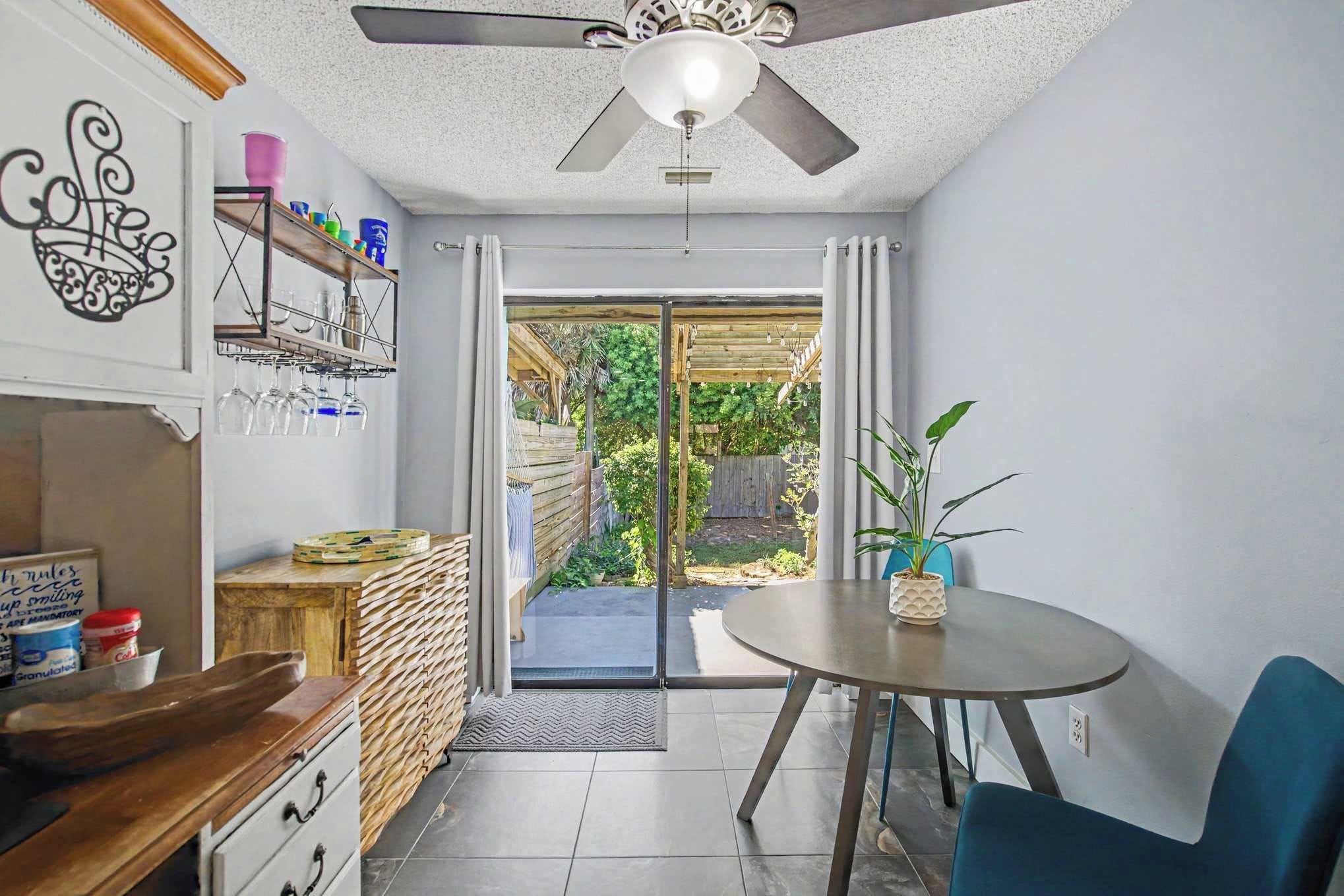 A modern kitchen with a dining area, a ceiling fan, and a view of the backyard.