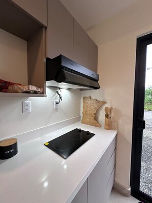 A kitchen with a black range hood, a white countertop, and a coffee container. - Sapphire House (La Perla)
