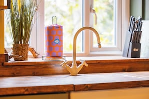 Eine Küchenarbeitsplatte mit einem weißen Wasserhahn, einem Blumentopf und einer Kerze auf einem Fensterbrett.