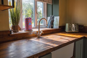 Eine Küche mit Holzarbeitsplatte, einem Spülbecken mit modernem Wasserhahn, einem Messerblock und einem Toaster.