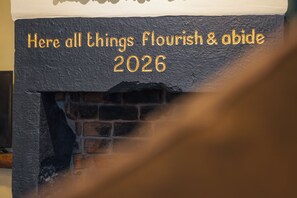 A fireplace with a plaque that reads 'Here all things flourish & abide 2026.' - The Botanist - Where Nature meets Luxury (Morecambe)
