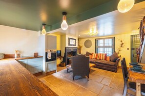 Eine moderne Küche mit einer Holzauskładung, einem Essbereich mit Holztisch, einer Couch mit Kissen und einer Kronleuchter.