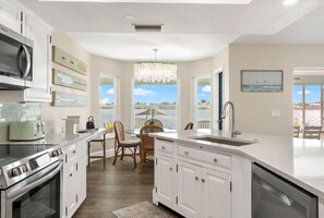 A modern kitchen with white cabinetry, a built-in oven, and a large island with a sink. - Schell-Nanigans Lake Front Sunrise (Cape Coral)