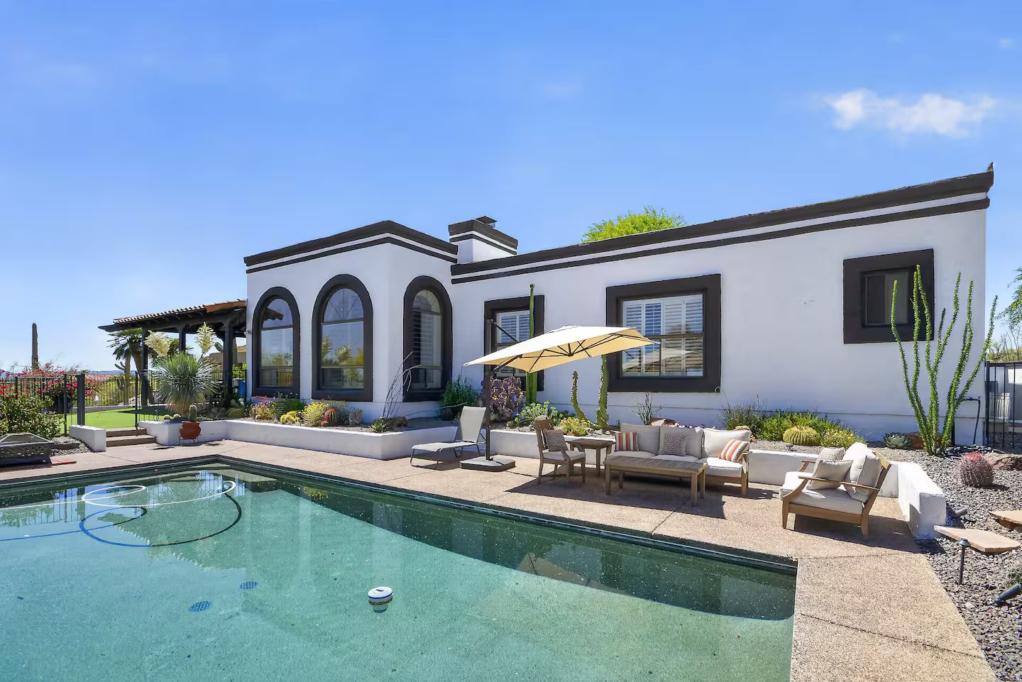 A modern house with a swimming pool, outdoor seating, and a garden.