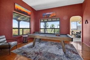 A pool table in a room with large windows, a chair, and a rug. - Tucson: Catalina Foothills Retreat (Tucson)